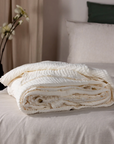 White Muslin Bedspread neatly folded on the end of a bed.