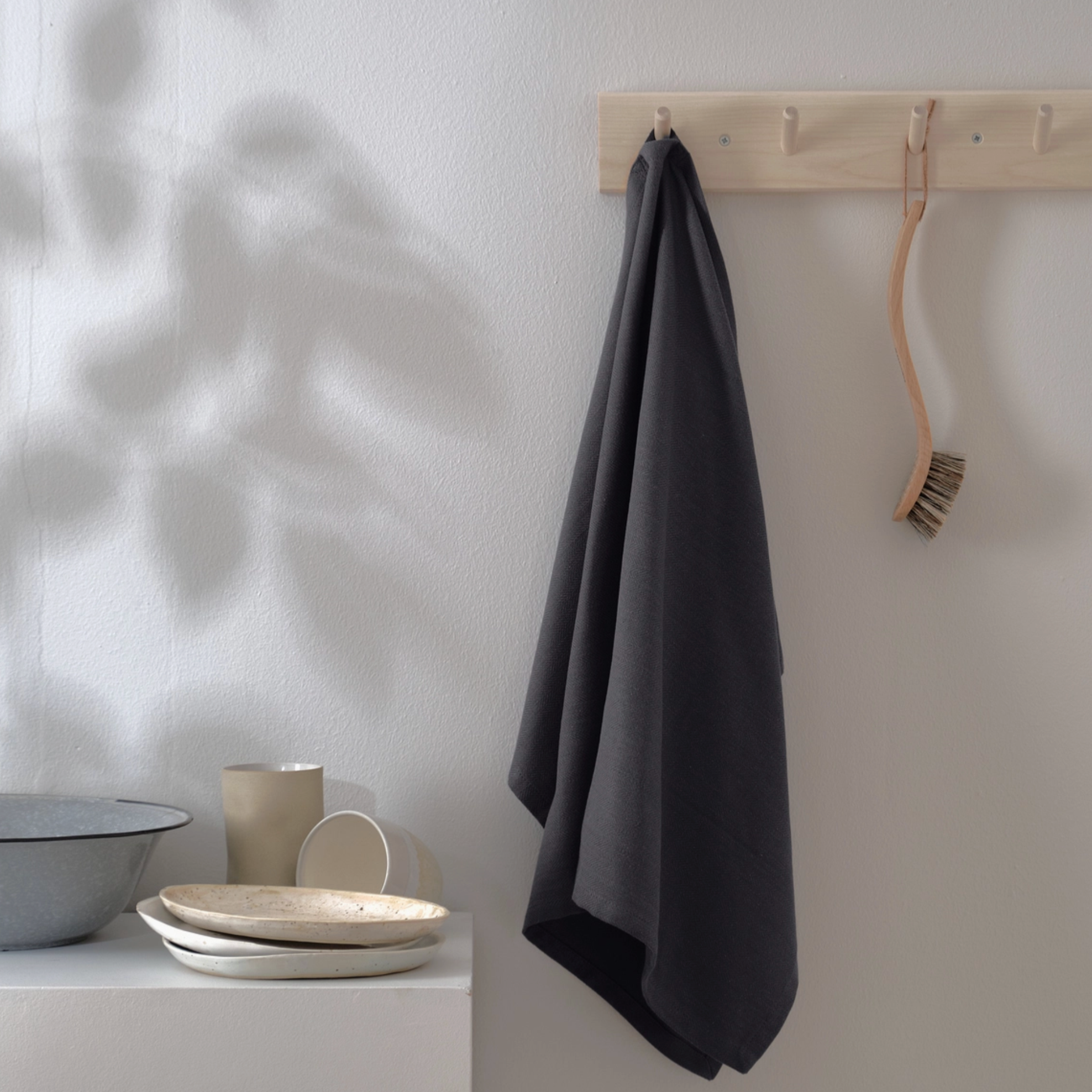 Dark grey kitchen towel hanging from wooden hook.