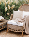 an outdoor living space with rattan armchair, jute rug and pampas grass.