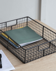 Wirework letter tray on desk with books.