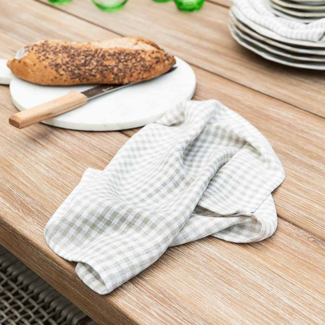 Natural gingham linen napkin folded up on table with bread board and knife.