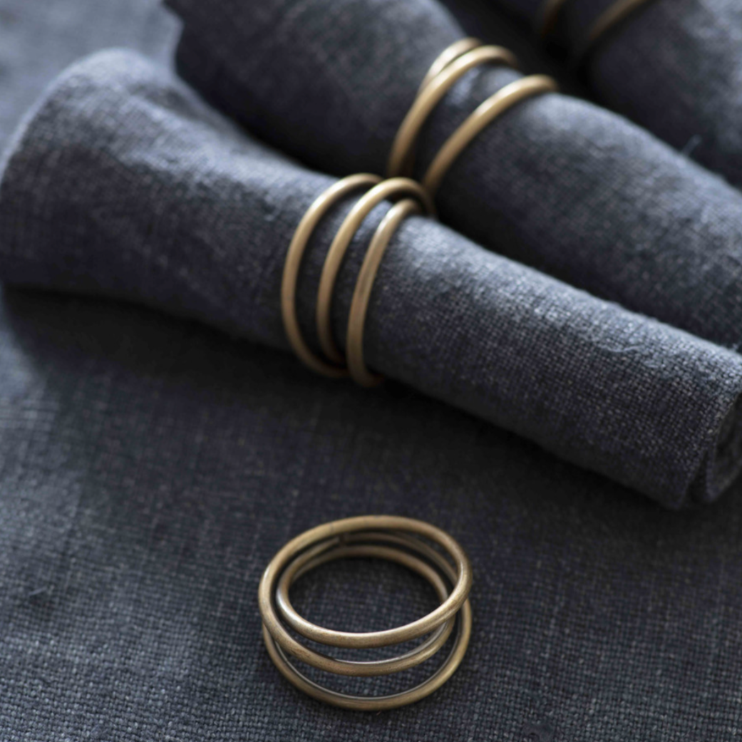 Rustic antique brass napkin rings wrapped around blue napkins.