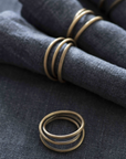 Rustic antique brass napkin rings wrapped around blue napkins.