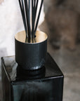 Sences Alang Alang Onyx Reed Diffuser on stone hearth.