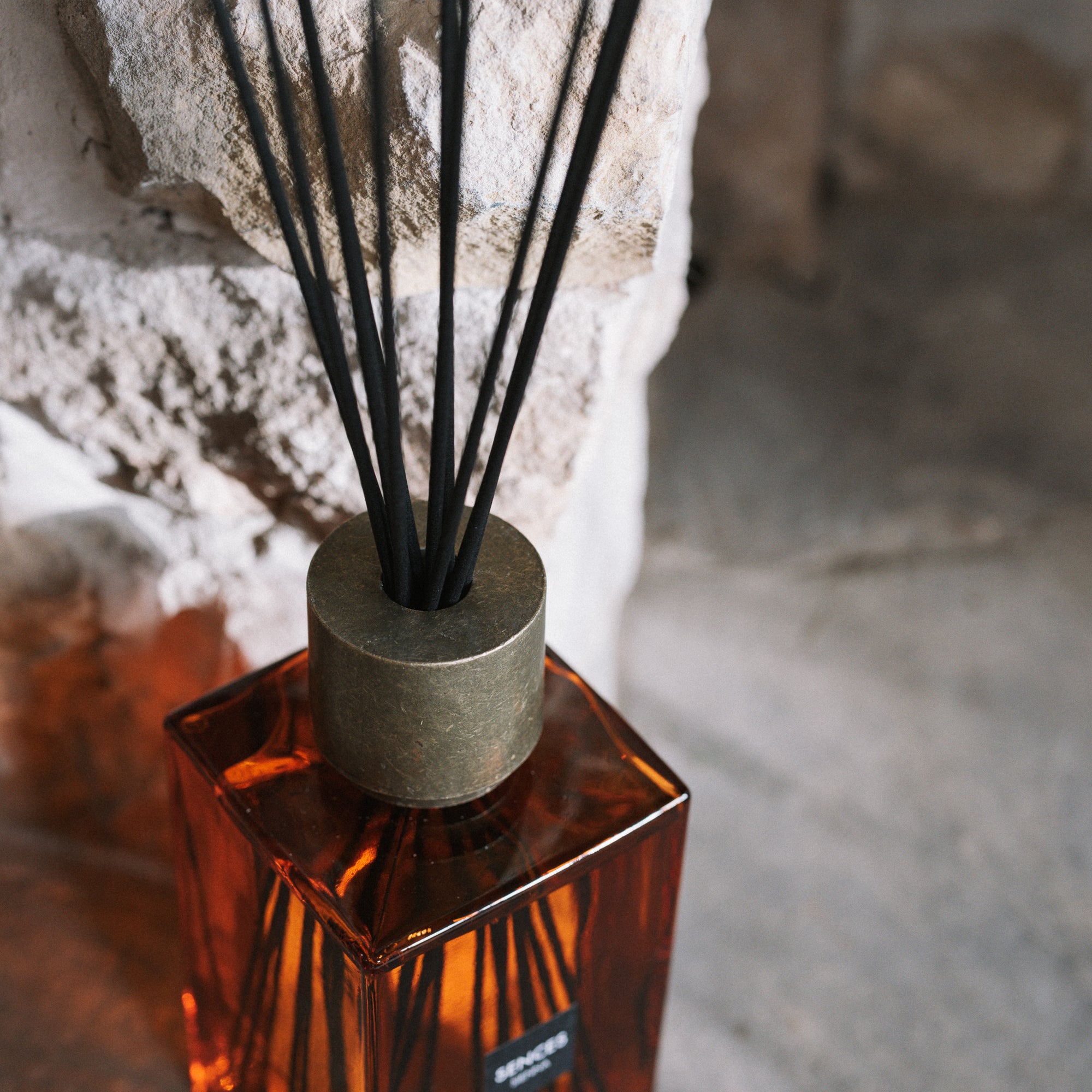 Detail shot of Sences Sienna reed diffuser on stone hearth.