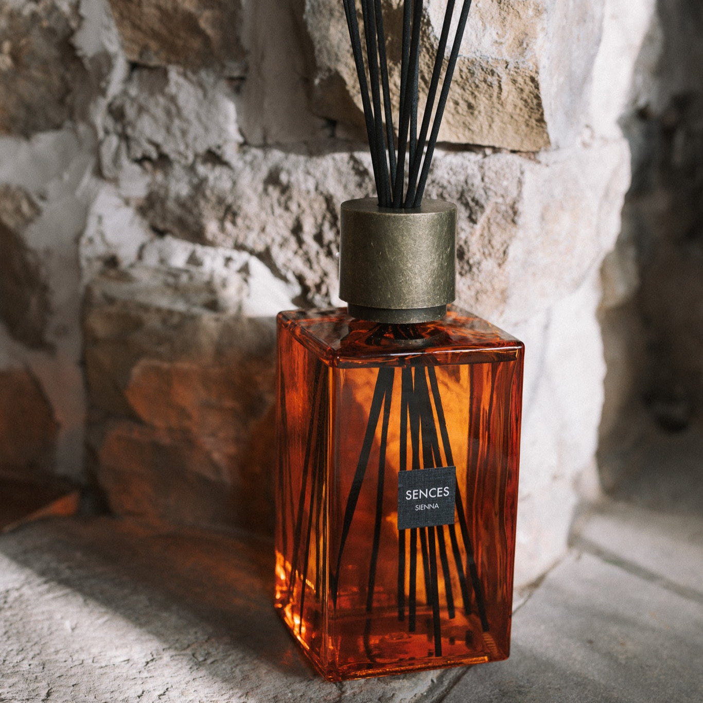 Large orange glass reed diffuser on stone hearth.