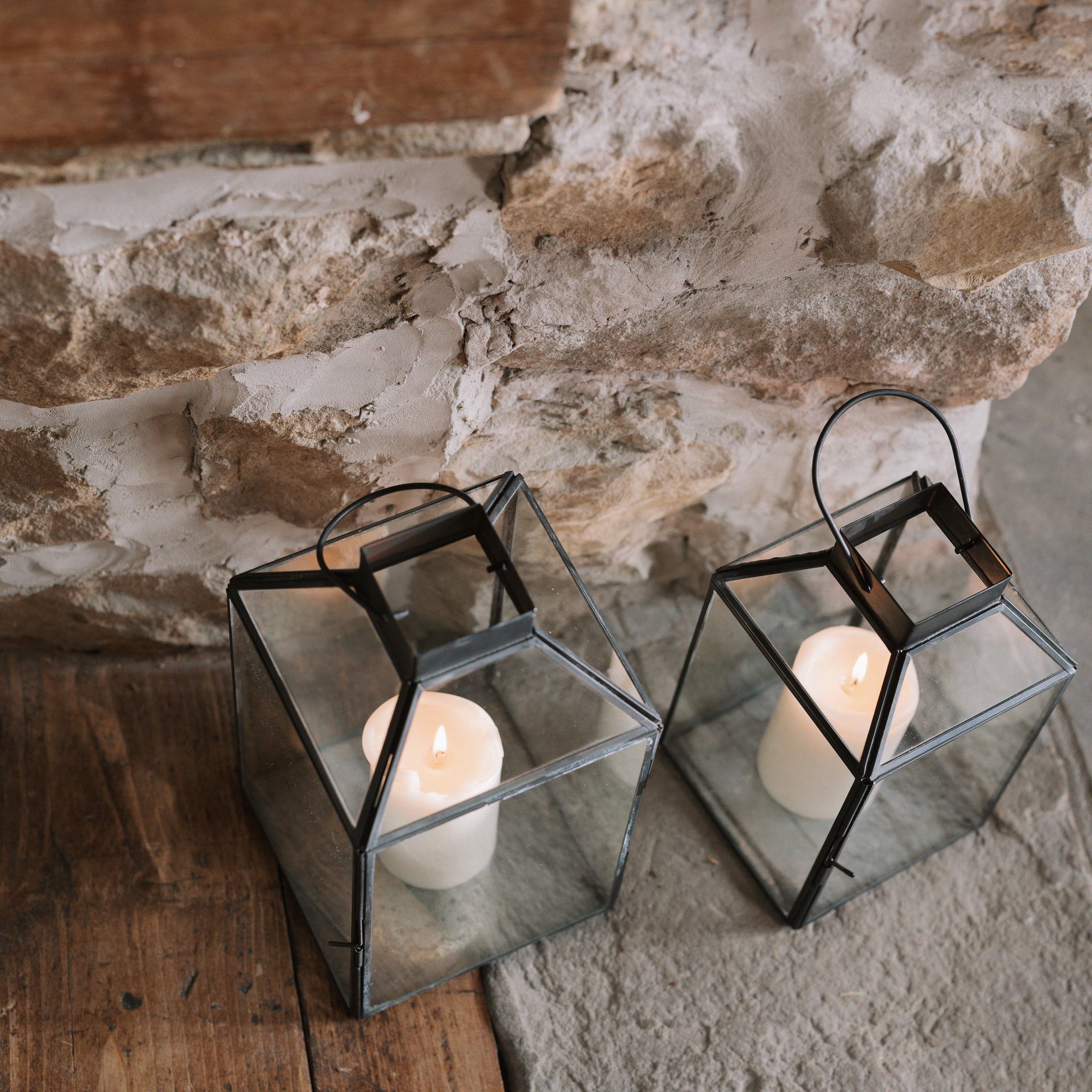 Set of two black and Glass Lanterns on stone hearth.