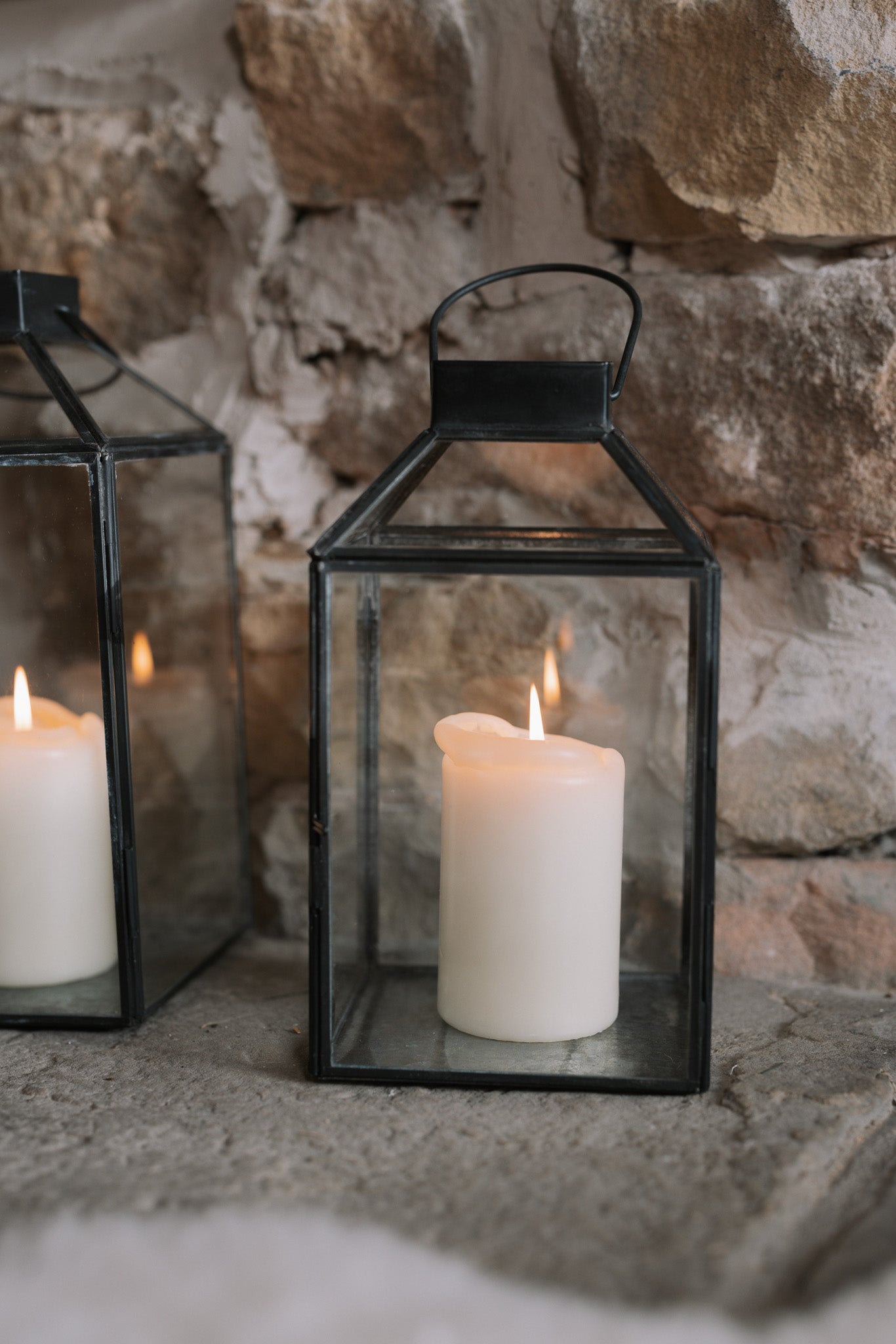 Set of two black and Glass Lanterns on stone hearth.