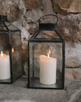 Set of two black and Glass Lanterns on stone hearth.