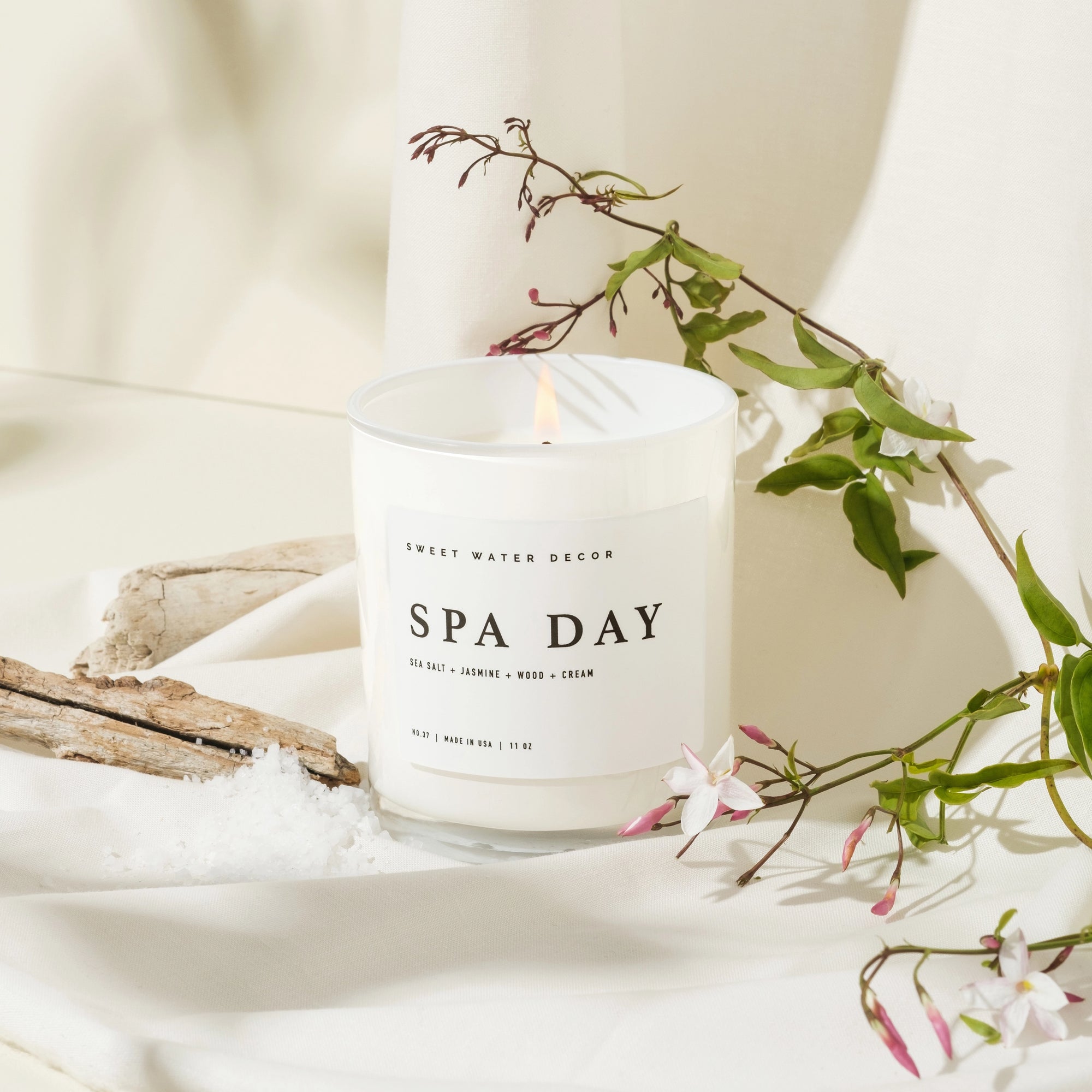 'Spa Day' soy candle on white background with flowers, wood and salt.