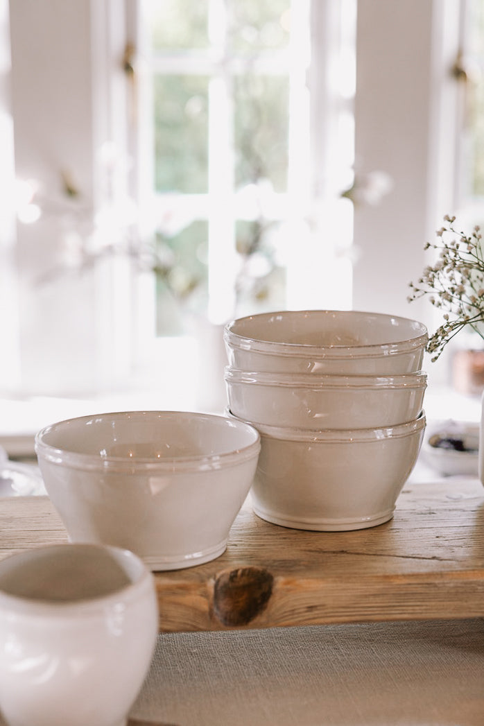 four white cereal bowls on wooden serving platter.