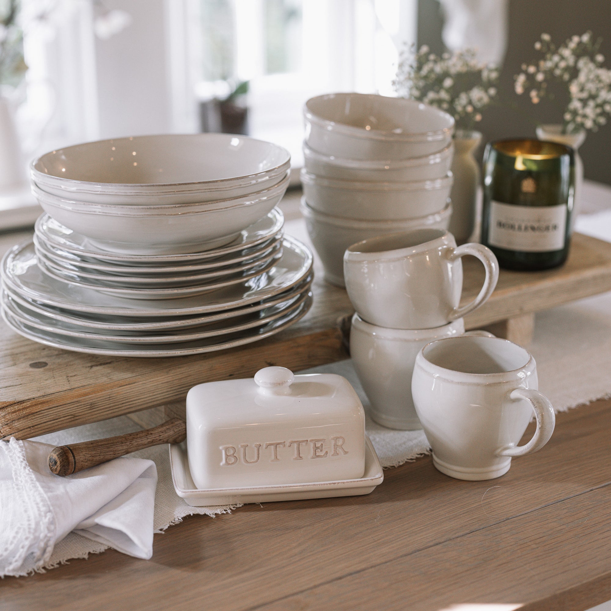 white ceramic dinnerware on wooden table with white linen runner.