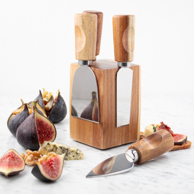 Cheese knife set attached to wooden block with figs and cheese around.