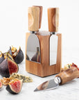 Cheese knife set attached to wooden block with figs and cheese around.