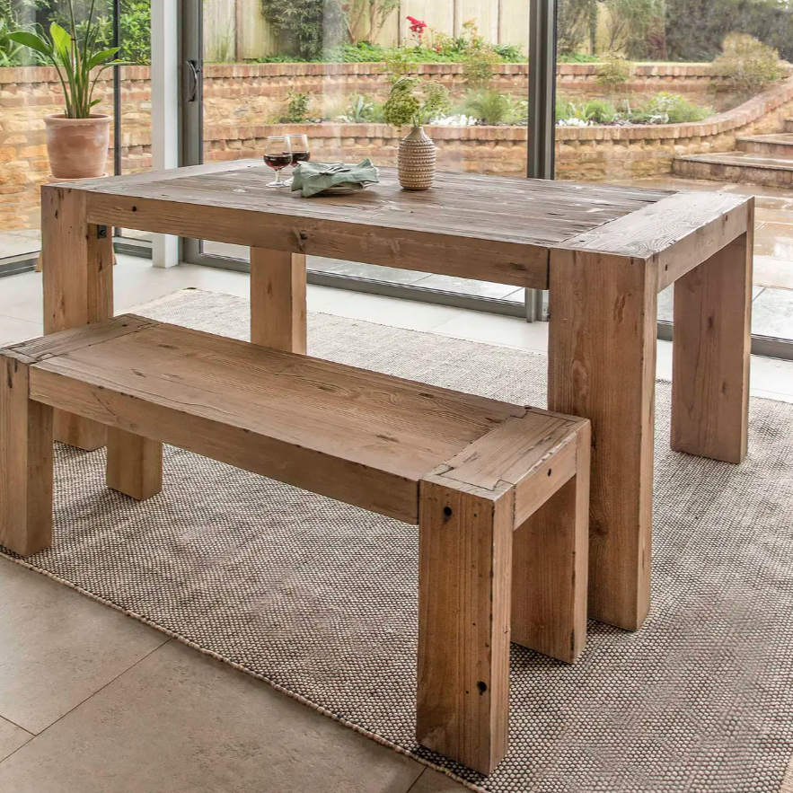 Solid Wood Dining Table on a neutral rug in a room with glass doors.