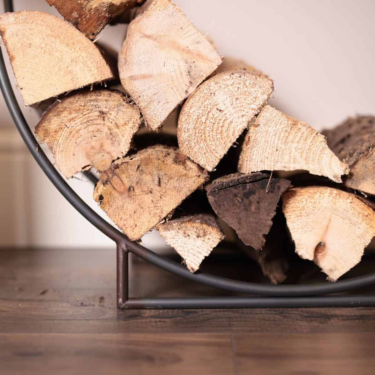 Close up of firewood on iron log carrier on wooden floor. 