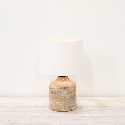 Mango wood small table lamp on wooden surface switched on.