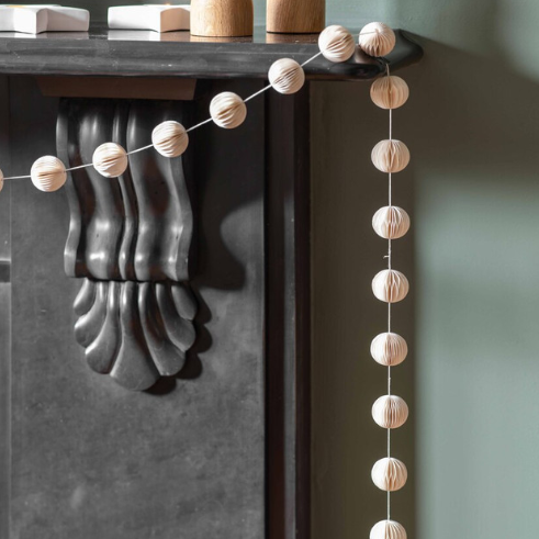 Warm white pom pom Christmas  garland on a black fireplace.