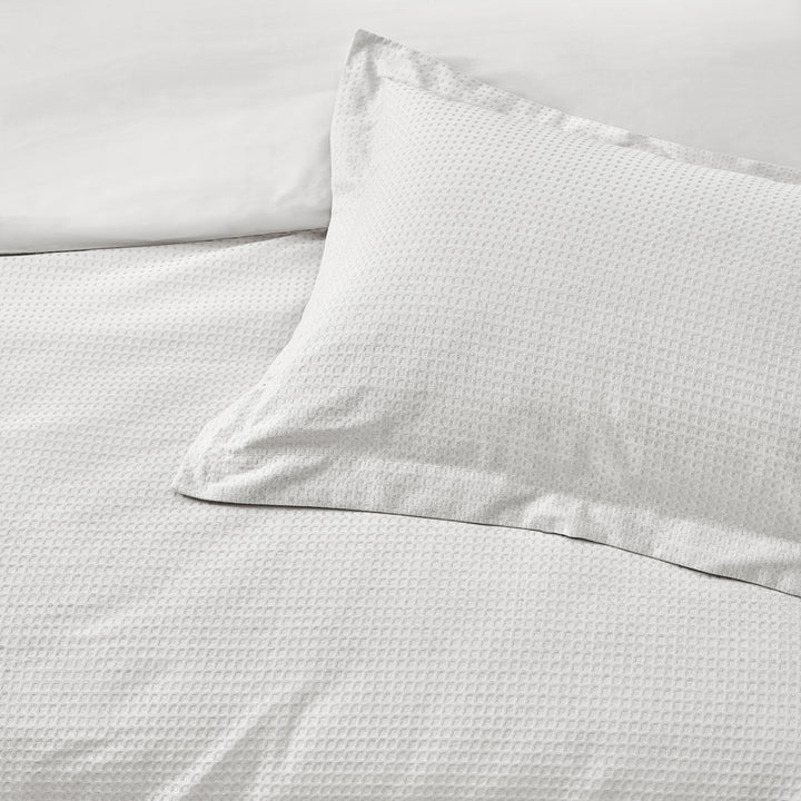 Close up of white waffle bedding set with pillow.