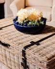 Wicker basket coffee table styled with blue bobble bowl with flowers in.