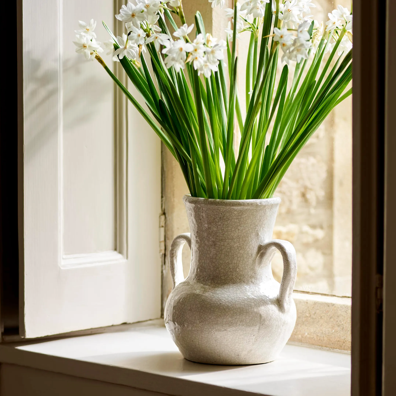 Wilma Ceramic Vase on windowsill with fresh stems on stone windowsill. 