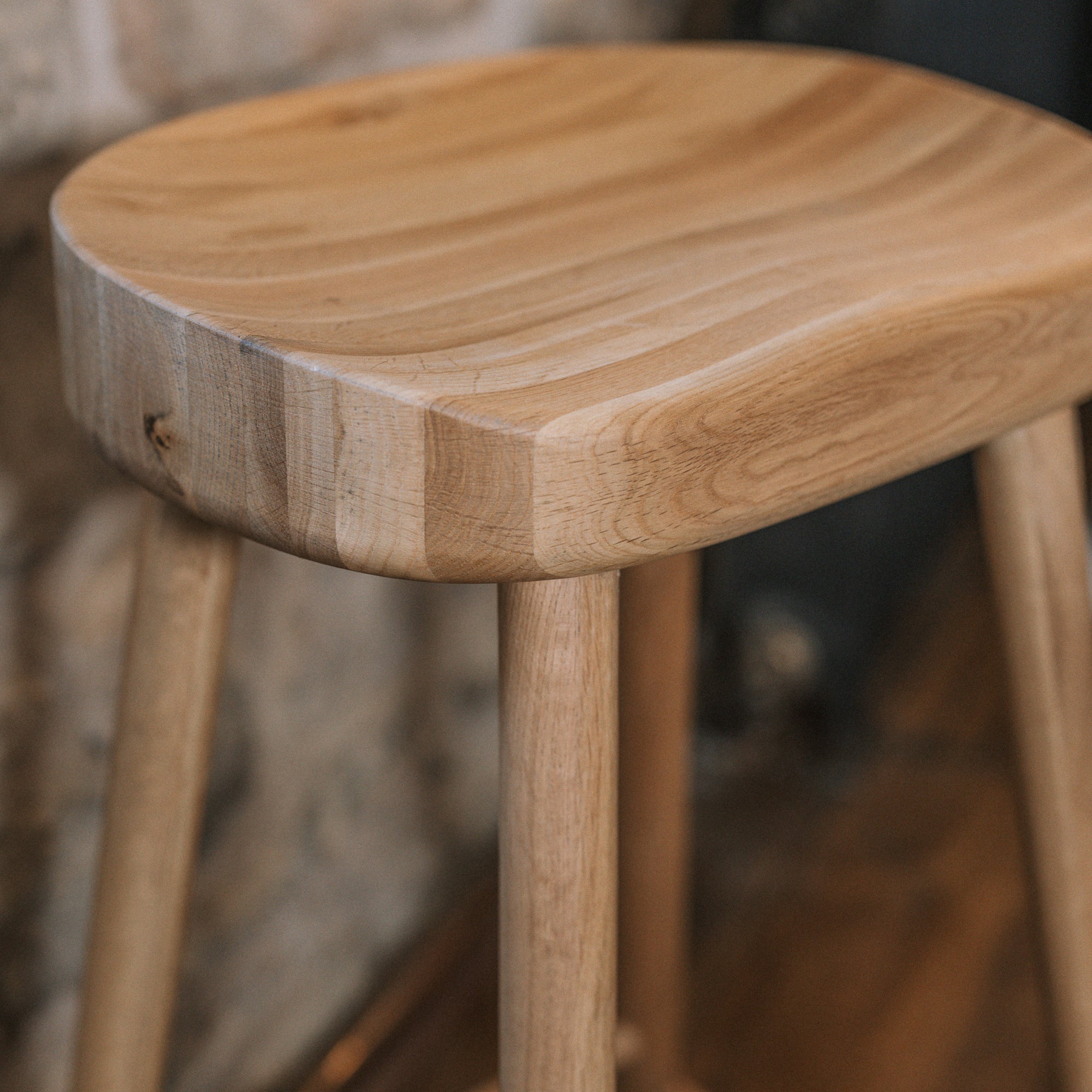 Detailed shot of Natural wooden backless barstool against stone wall.