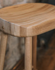 Detailed shot of Natural wooden backless barstool against stone wall.