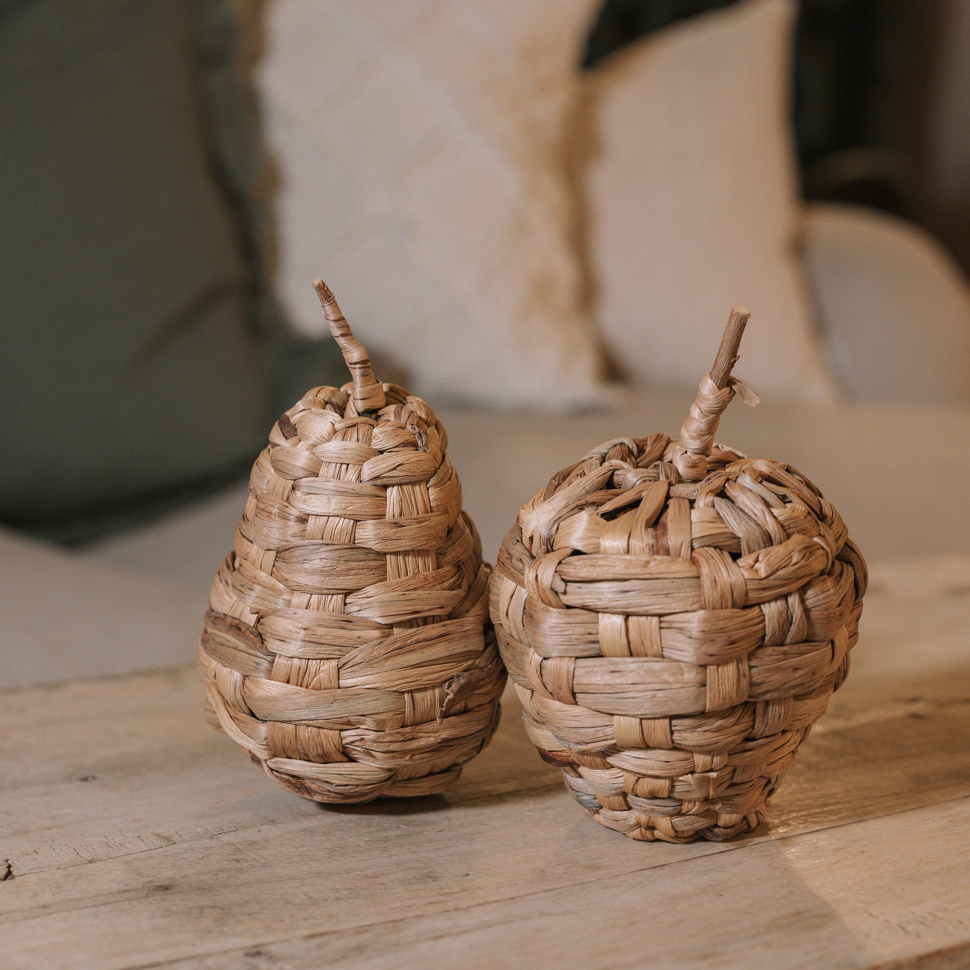 Woven Apple and Pear Ornaments on wooden table.