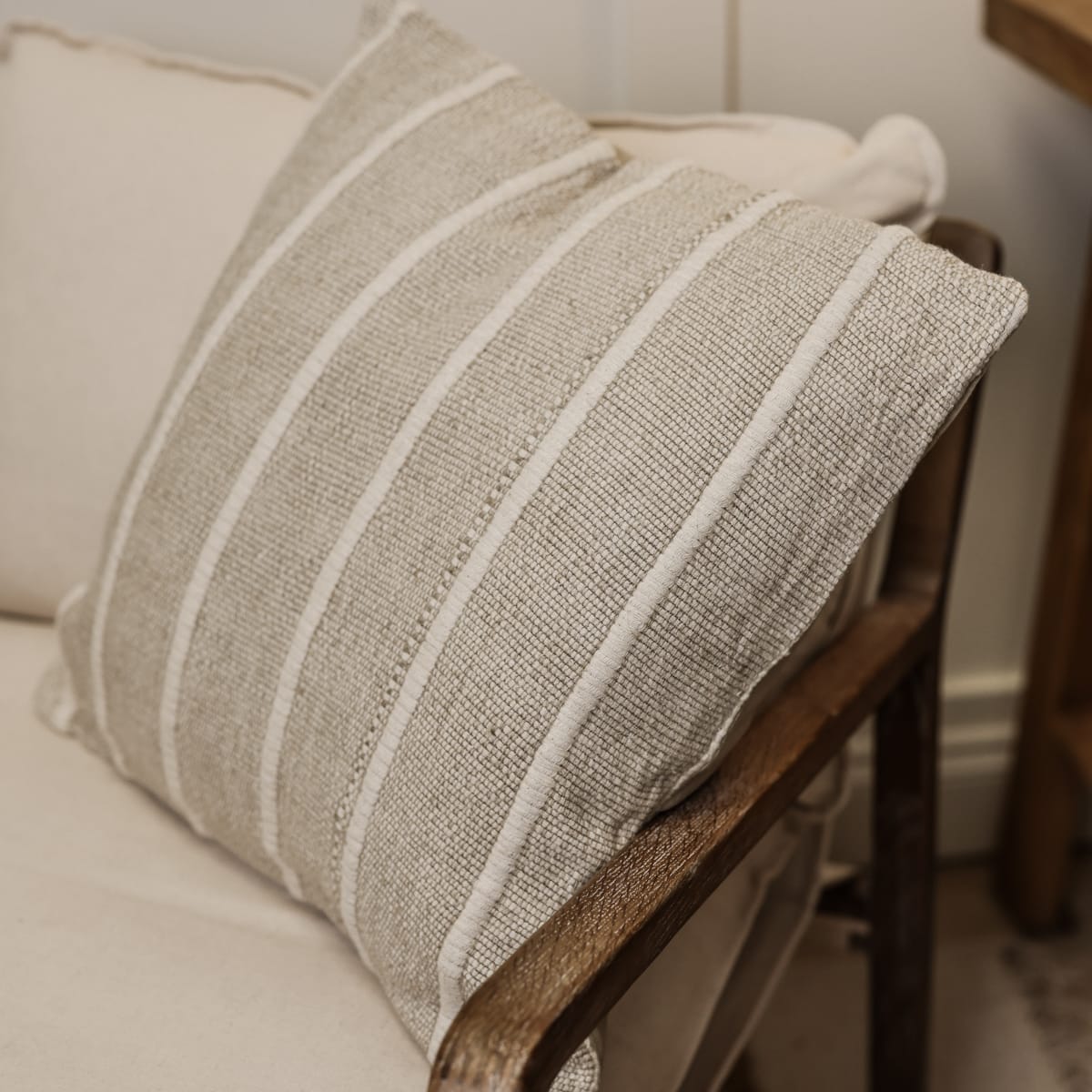 Striped neutral coloured square cushion from side view on armchair.n