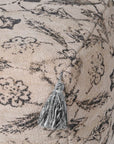 Close up of grey tassels on vintage patterned pouf.