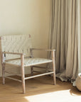 The Lulworth Rustic Wooden Armchair in a neutral living room with a small basket and plant.