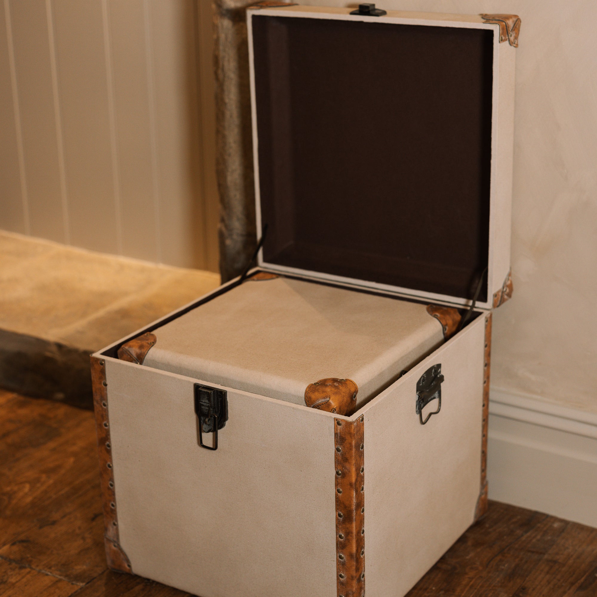 Set of two linen storage trunks with faux leather panelling on wooden floor.