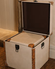 Set of two linen storage trunks with faux leather panelling on wooden floor.