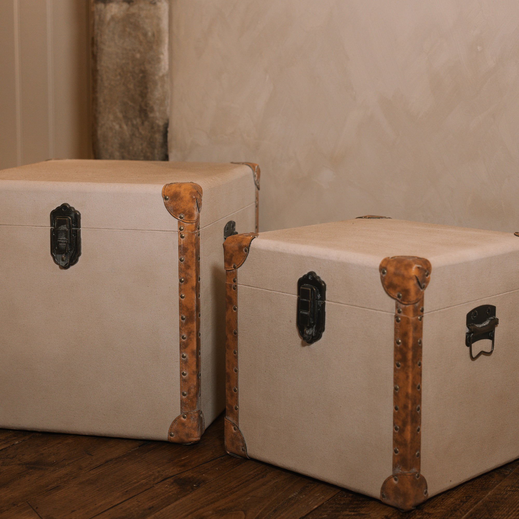 Set of two linen storage trunks on wooden floor.